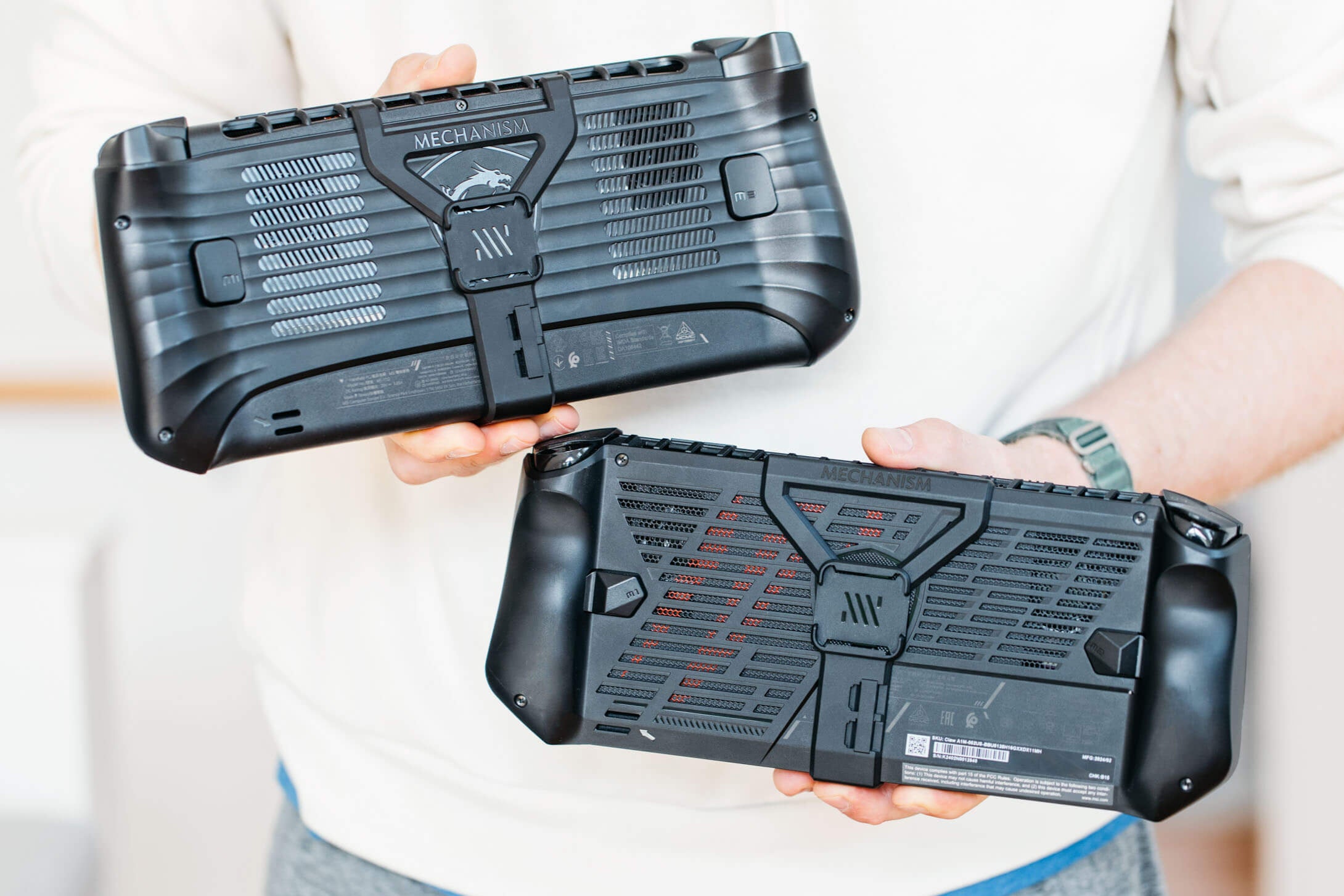 Two consoles, an MSI Claw 7 and and MSI Claw 8 held by a person against a white background