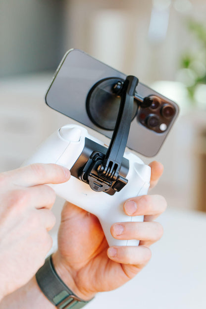 A person attaches a phone to their Xbox controller using the Mechanism Xbox Controller Grip and Phone Mount