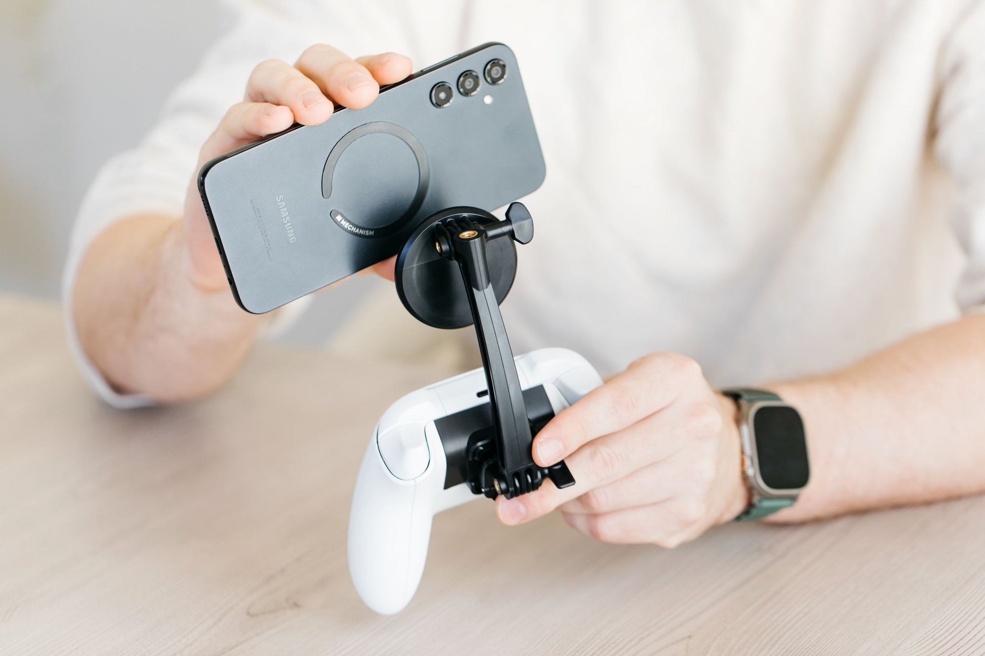 Person holding a smartphone with a gaming controller attachment on a light background